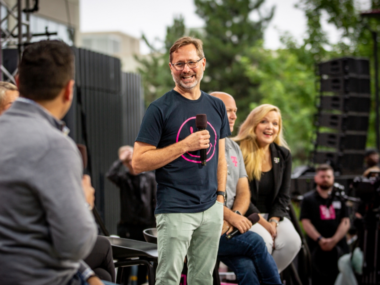 Mike Sievert en el escenario con los miembros del equipo directivo sénior, sonriendo.