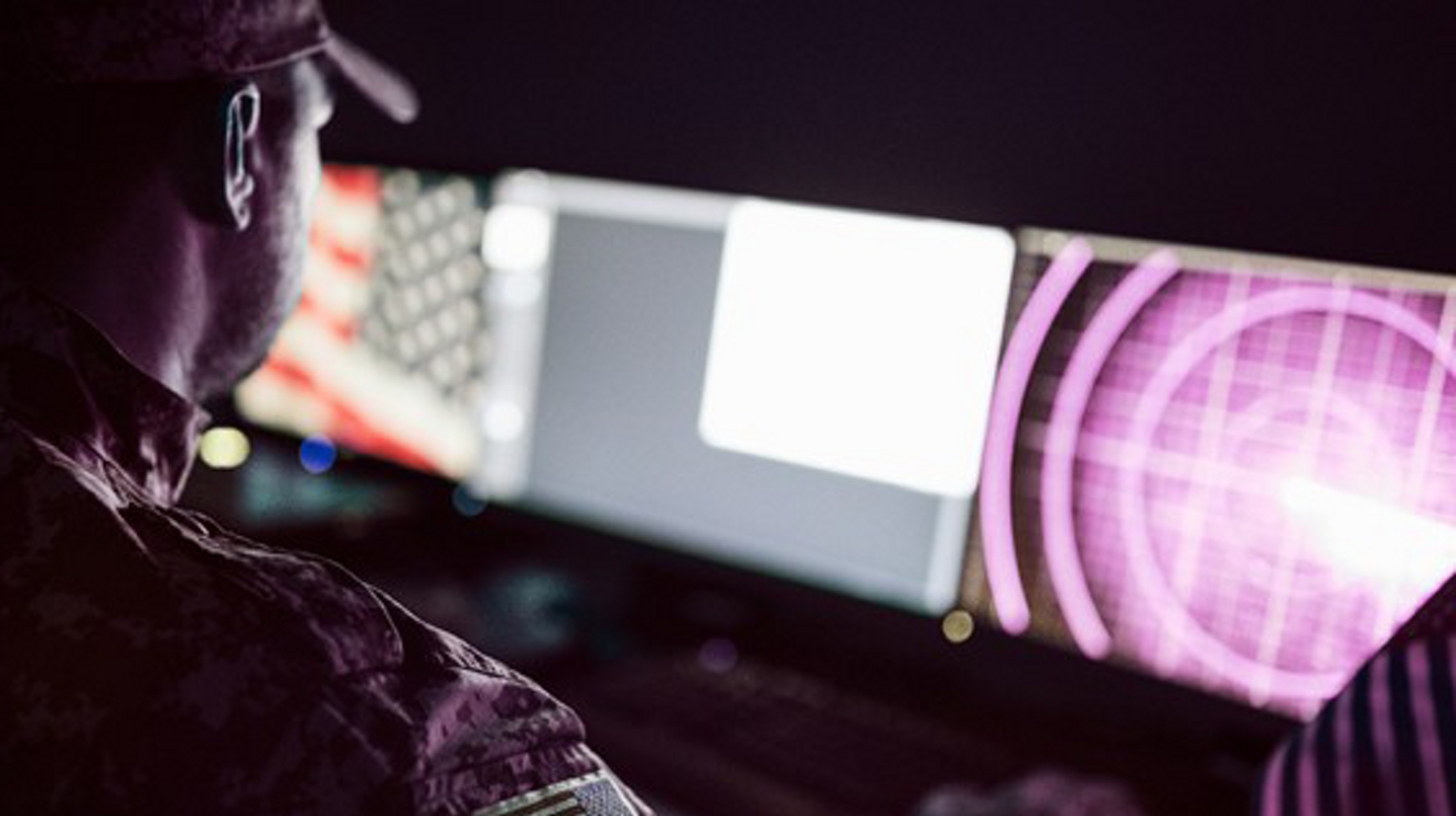 Hombre en uniforme camuflado señalando una pantalla que muestra un mapa del mundo