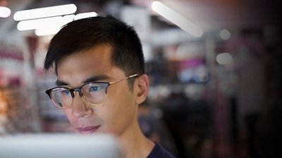 Hombre con gafas mirando la pantalla de su computadora.
