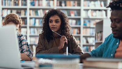 Grupo de personas en una biblioteca mirando una laptop