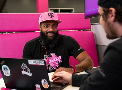 Empleado de T-Mobile con gorra magenta, sonriendo a un cliente.